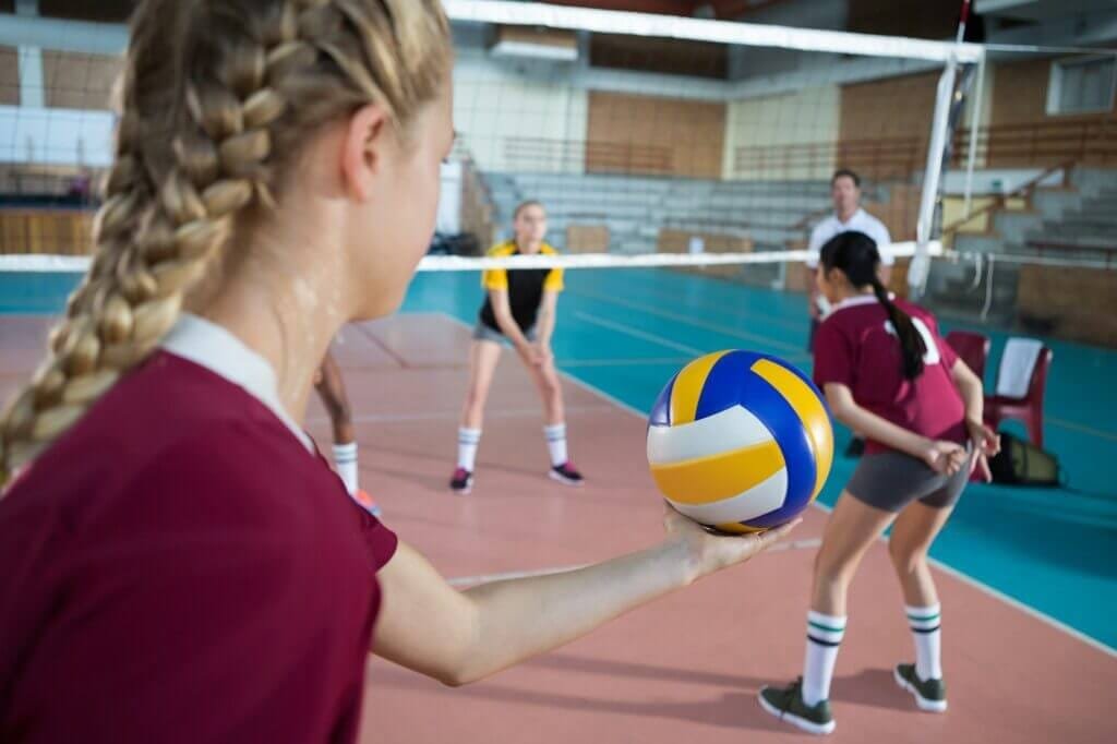 Female players playing volleyball in the court